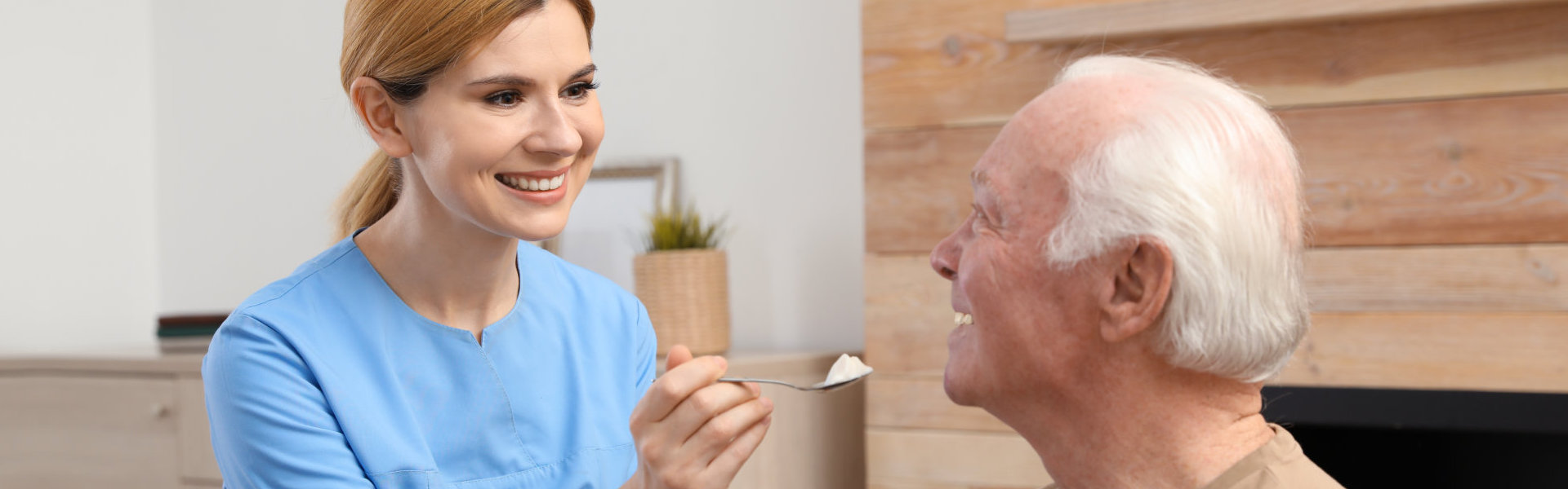 aide smiling while feeding the senior man