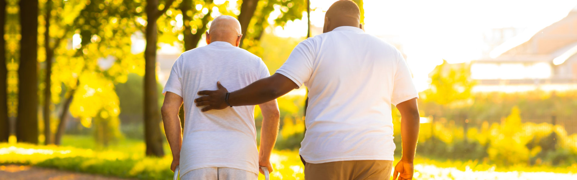 Caregiver is teaching old man to walk with walker